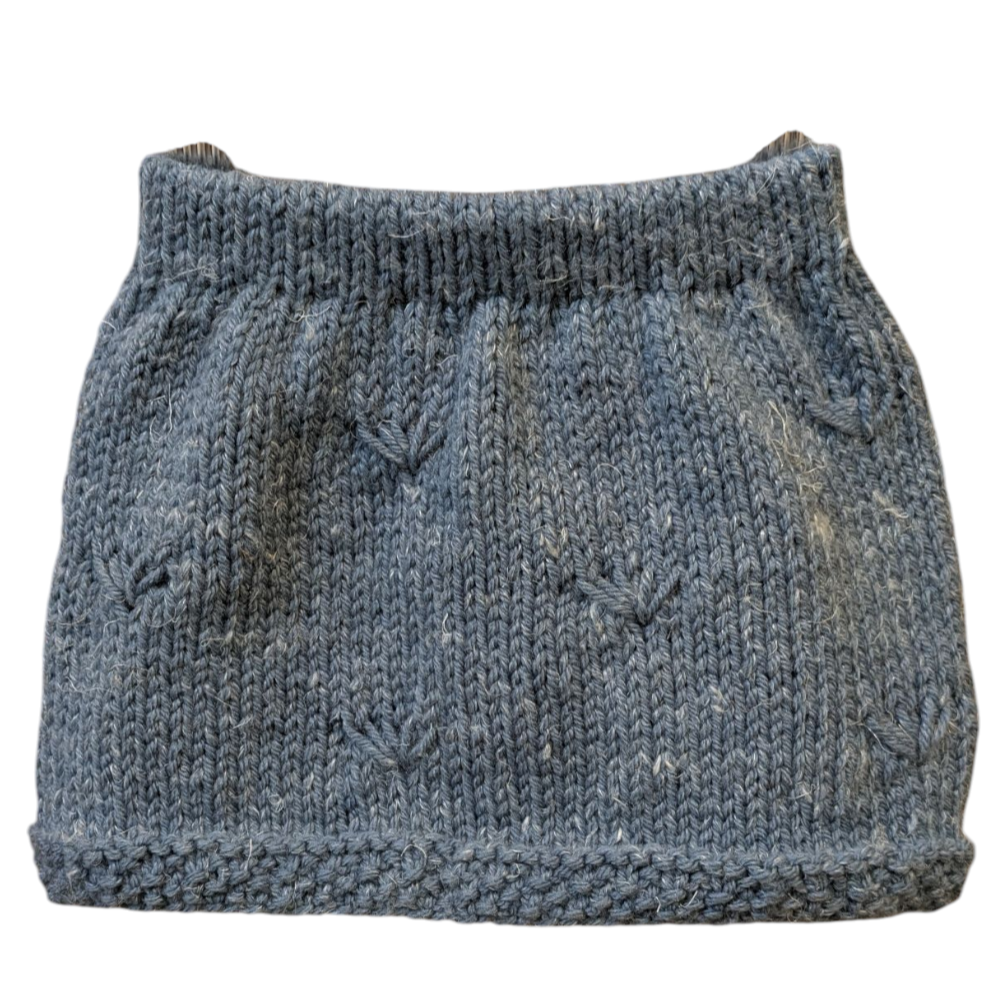 A hand-knit girls skirt in a heathered muted blue color, featuring textured hem and knit pattern details and a ribbed waistband.
