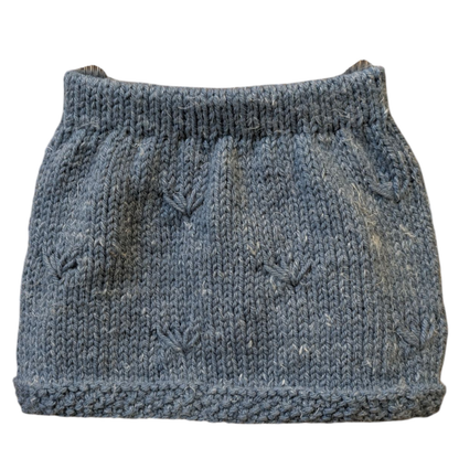A hand-knit girls skirt in a heathered muted blue color, featuring textured hem and knit pattern details and a ribbed waistband.